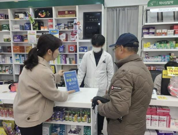 약국에서 방문객에게 치매관리사업을 홍보하고 있다